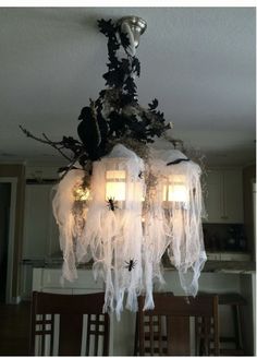 the chandelier is decorated with white fabric and black spiderweaves on it