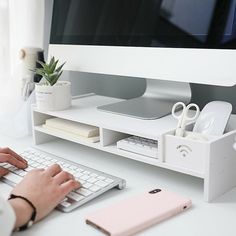 a person typing on a keyboard at a desk with an apple computer in the background