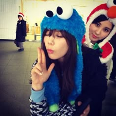 two girls in costumes posing for the camera with one holding up her hand and the other wearing a santa hat