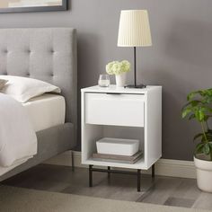 a bedroom with a bed and nightstand next to a plant on the side walk way