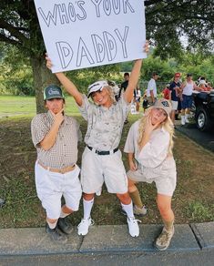 three people holding up a sign that says who's your daddy?