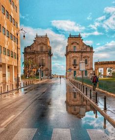 people are walking down the street in front of some old buildings with water puddles