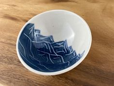 a blue and white bowl sitting on top of a wooden table