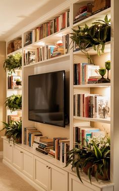 a living room with bookshelves and a flat screen tv mounted on the wall