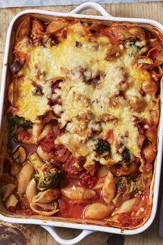 a casserole dish filled with pasta and vegetables on top of a wooden table