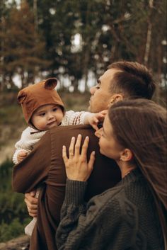 a man holding a baby in his arms while wearing a bear hat and looking at the camera