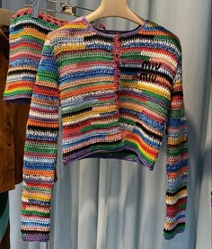 two colorful sweaters hanging on a clothes rack