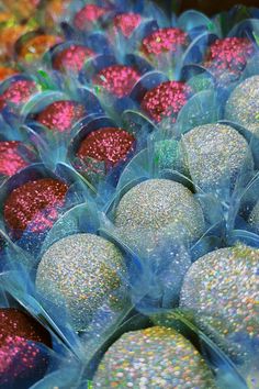 plastic containers filled with glitter covered donuts on top of each other in different colors