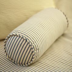 a blue and white striped pillow sitting on top of a bed next to a pillow