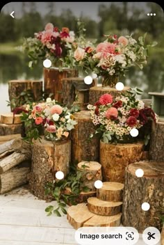 there are many vases with flowers in them on the table next to logs and candles