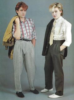 two young men standing next to each other in front of a gray background wearing ties