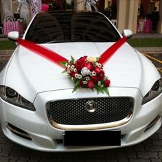 a wedding car decorated with red and white flowers