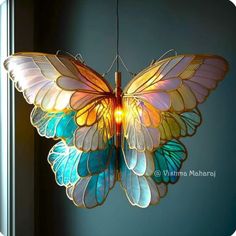 a multicolored butterfly light hanging from a ceiling in a room with blue walls