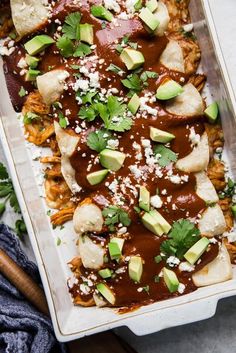 an enchilada dish with meat, cheese and avocado on top