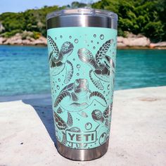 there is a cup that has some sea animals on it and water in the background