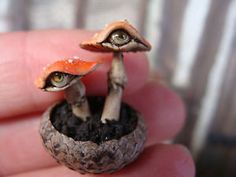 two tiny figurines are sitting in a potted plant with dirt on the ground