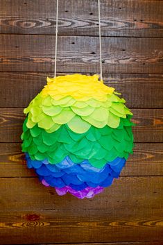 a colorful paper ball hanging from strings on a wooden wall with string attached to it