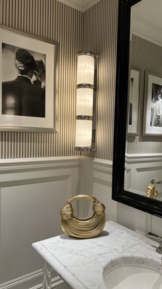 a white sink sitting under a bathroom mirror next to a wall mounted faucet