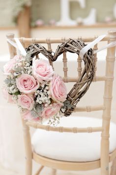 a heart shaped wreath with pink roses and baby's breath sits on a chair