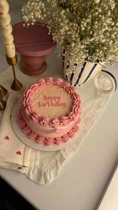 a birthday cake sitting on top of a table next to a vase filled with flowers