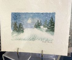 a watercolor painting of a snowy night with trees and moon in the sky on paper