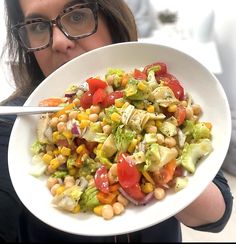 a woman holding a plate with a salad on it