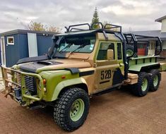 an army truck parked in front of a building with another vehicle on the trailer behind it