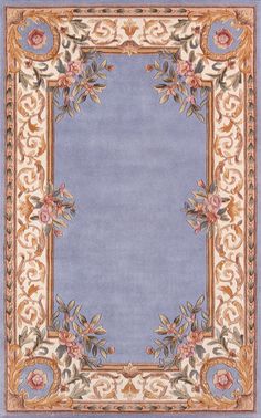 a blue and beige rug with an ornate border in the center, surrounded by flowers