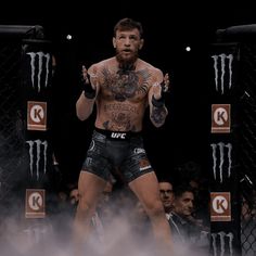 a man with tattoos standing in front of a cage