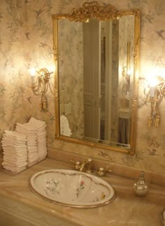 a bathroom sink sitting under a large mirror next to a wall mounted faucet