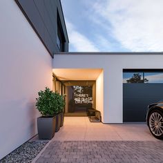 a car is parked in front of a white building with a black door and windows