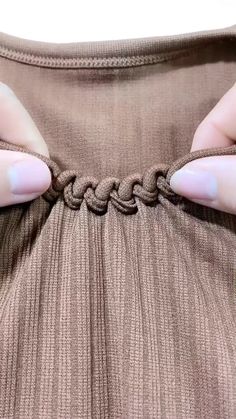 a woman's hands pulling on a piece of fabric with a knot around it