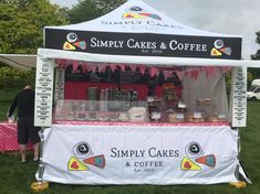 a tent that has some cakes and coffee on it with people standing in the background