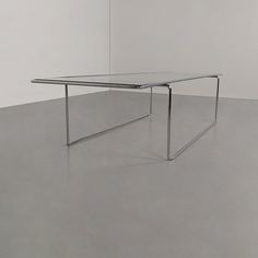 a glass table sitting on top of a floor next to a white wall in an empty room