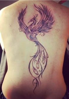 a woman's back with a bird tattoo on her left side ribcage