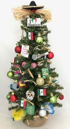 a small christmas tree decorated with mexican ornaments and sombrero hat on top, against a white background