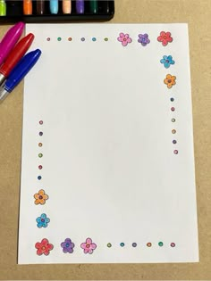 a white paper with flowers and dots on it next to two colored crayons