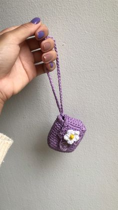 a hand holding a small crocheted purse with a flower on it's string