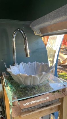 a glass bowl sitting on top of a table next to a metal faucet