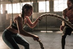 a man and woman holding a large snake in an indoor gym area with other people