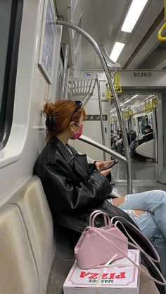 a woman sitting on a subway looking at her phone