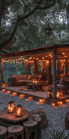 an outdoor living area with candles lit up on the ground and trees in the background