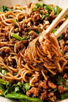 a bowl full of noodles and meat with chopsticks sticking out of the top