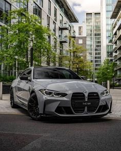 a grey car parked in front of some tall buildings on the side of a road