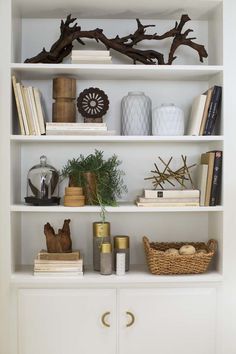 a white book shelf filled with lots of books and vases on top of it