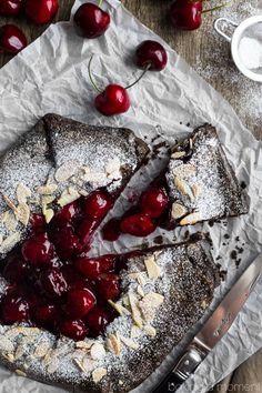 a piece of cake with cherries on top and some powdered sugar next to it