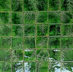 a green tile wall with lots of leaves on it