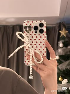 a woman is holding up her phone case with pearls on it