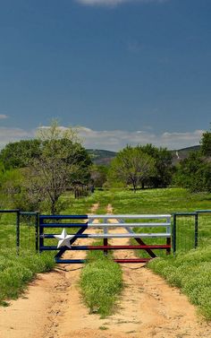 an open gate leading to a dirt road with a star painted on the top and bottom