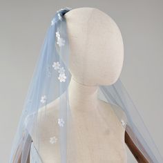 a white mannequin wearing a blue veil with flowers on it